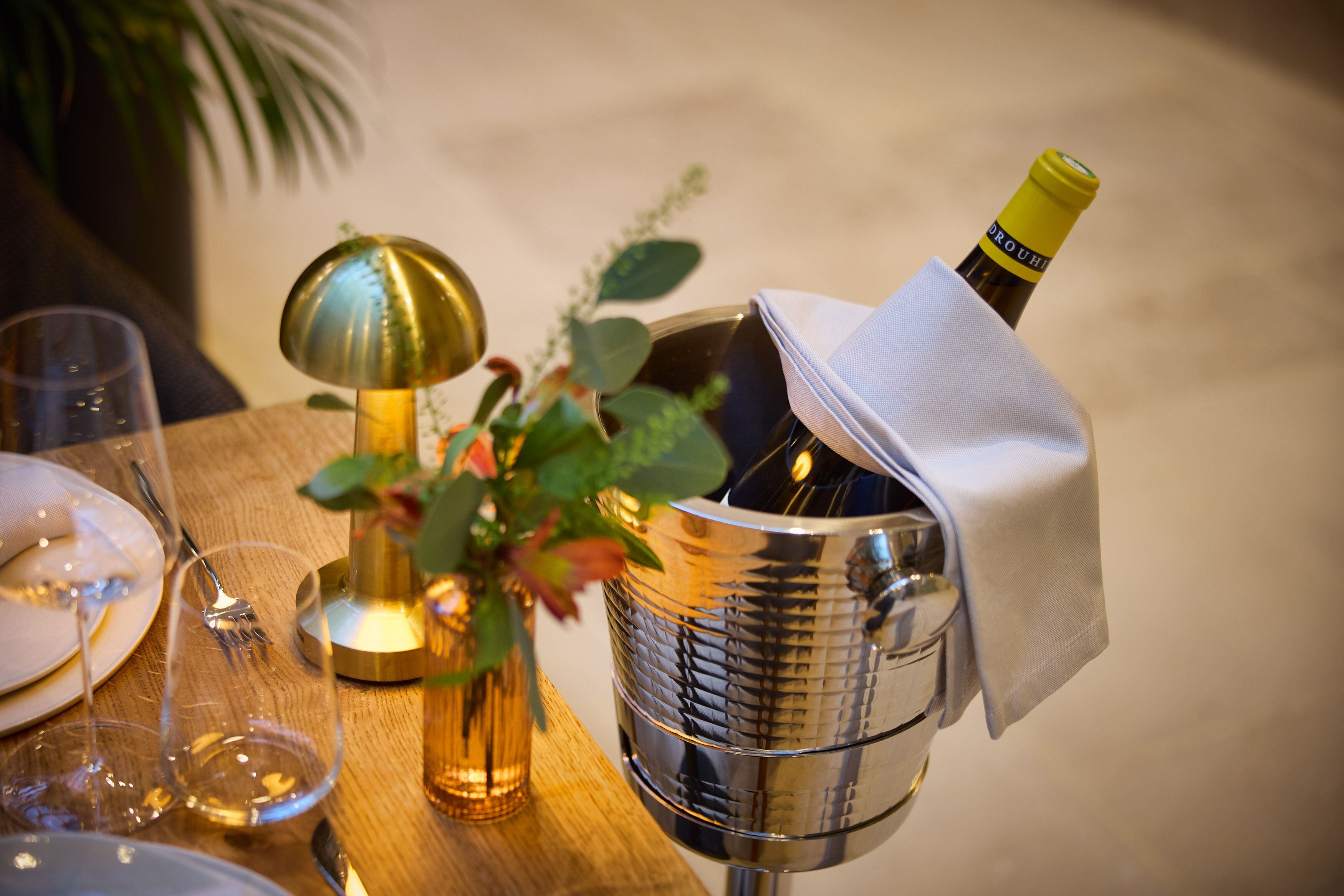 Una mesa con una botella de vino, una copa y una vela.