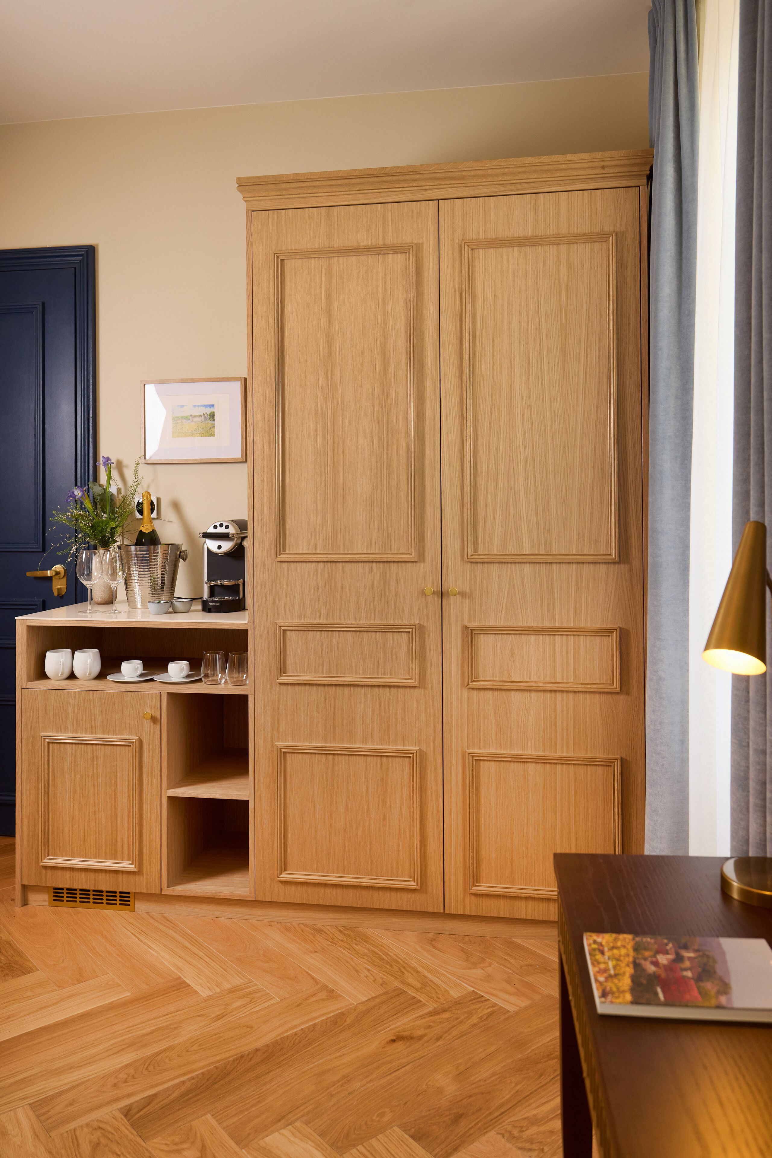 Una habitación con un armario de madera, una mesita con una lámpara y una cafetera.