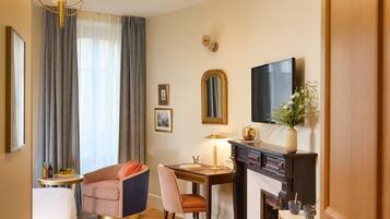 Una habitación de hotel con cama, escritorio, silla, televisor, chimenea y zona de comedor.