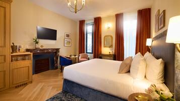 A hotel room with a large bed, a flat-screen TV, a fireplace, a desk, and a view of the outdoors.