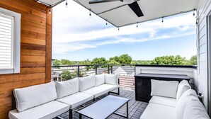 Un espacio de descanso techado al aire libre con ventilador de techo, sofá y mesa.