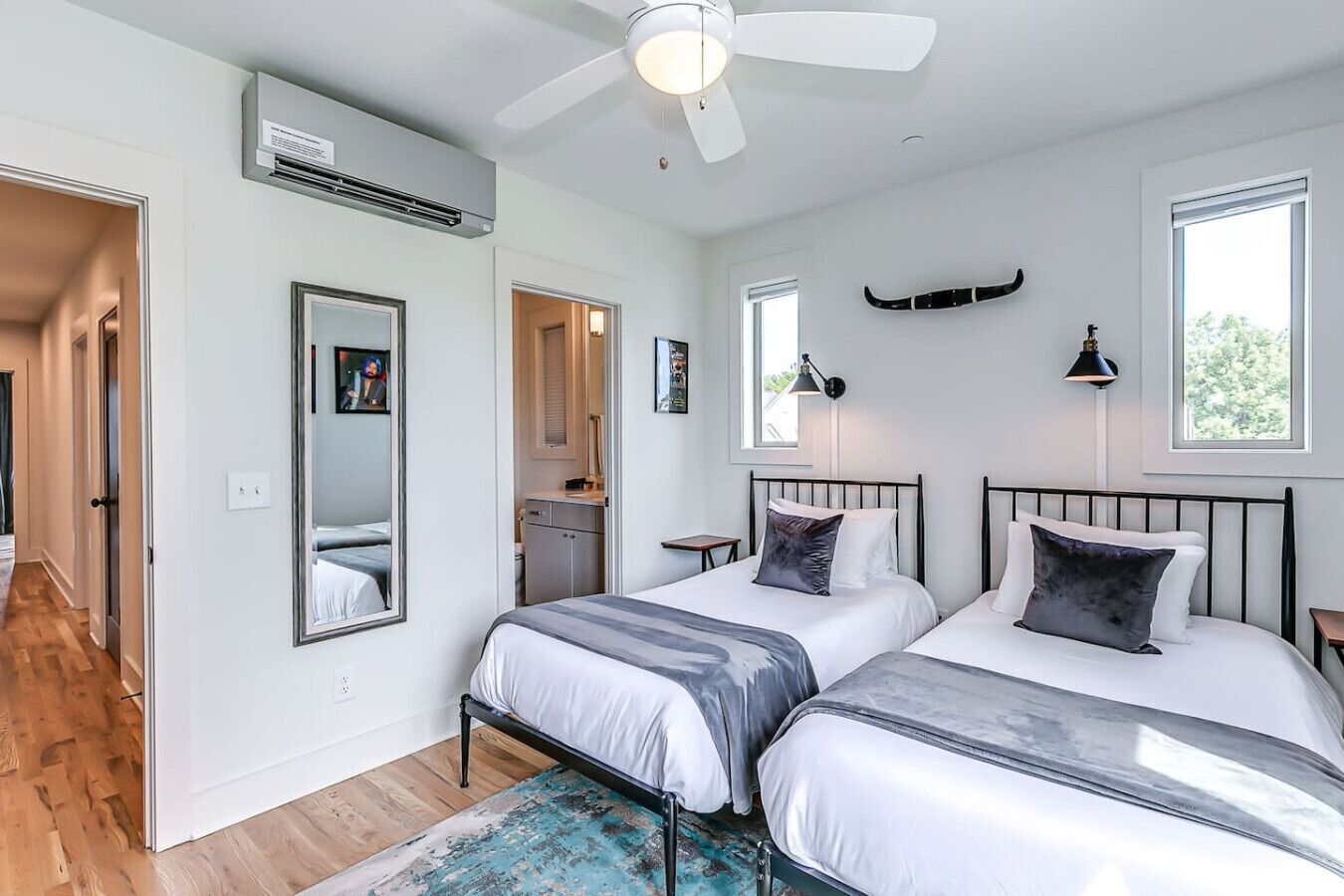 Una camera da letto moderna con due letti, una ventola a soffitto e un'ampia finestra.
