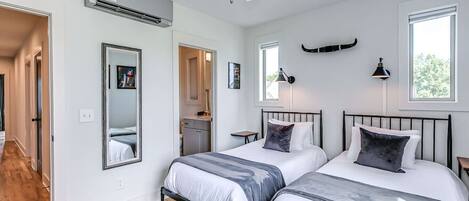 Una camera da letto moderna con due letti, una ventola a soffitto e un'ampia finestra.