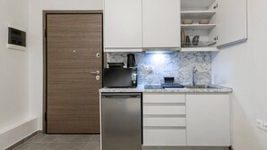 Eine kleine Küche mit Geschirrspüler, Kaffeemaschine und Spüle.