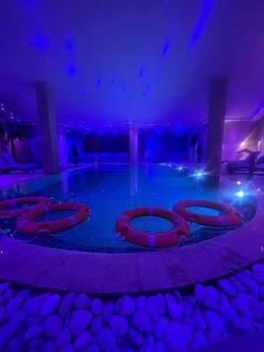 An indoor swimming pool with a stone border and red lifebuoys. - Hôtel le paquebot (Filfila)