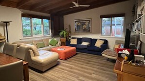 Un salón amplio con techo de madera, dos sofás, una mesa de centro y una estantería.