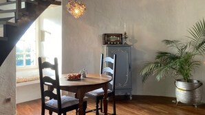 A dining area with a wooden table and chairs, a vintage radio, and a potted plant. - Château de la Preuille (Montaigu-Vendée)