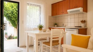 A kitchen with white cabinets, a white countertop, and a window with sheer curtains.