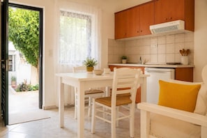 A kitchen with white cabinets, a white countertop, and a window with sheer curtains.