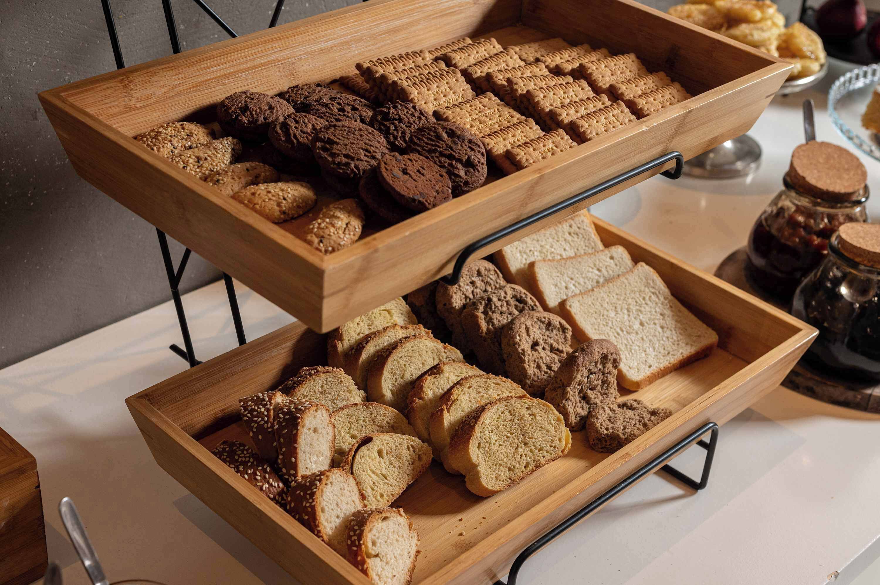 Een houten dienblad met verschillende soorten brood en koekjes.