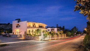A modern two-story house with a balcony, a driveway, and a street with light trails.