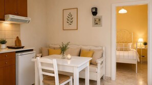 A kitchen with a white table, a white sofa, and a dining area.