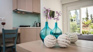 Een moderne keuken met lichte houten kastjes, een blauwgroene stoel en twee blauwe vazen met paarse bloemen op het aanrecht.