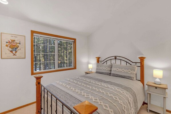 A bedroom with a bed, a window, a nightstand, and a wall-mounted lamp. - Single-Level 3BR | AC | River, Trails (Bend)