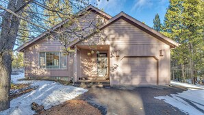 A single-story house with a garage, surrounded by trees and a snow-covered driveway. - Single-Level 3BR | AC | River, Trails (Bend)