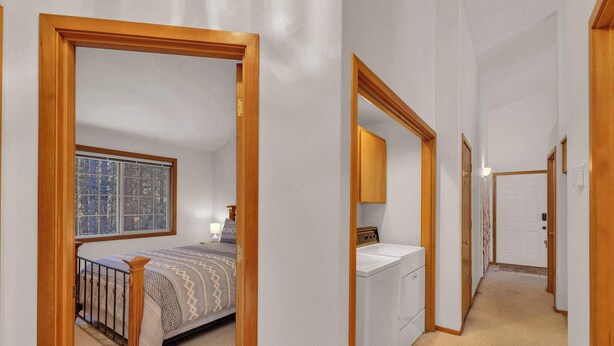 A bedroom with a bed, a window, and a washing machine in a hallway. - Single-Level 3BR | AC | River, Trails (Bend)