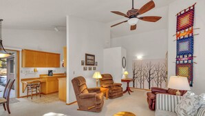 A living room with a sofa, armchairs, a coffee table, and a dining area with a kitchen in the background. - Single-Level 3BR | AC | River, Trails (Bend)