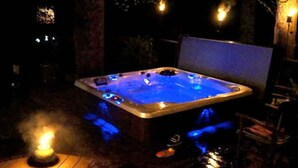 Un jacuzzi con una cubierta de madera y una pared de piedra al fondo.