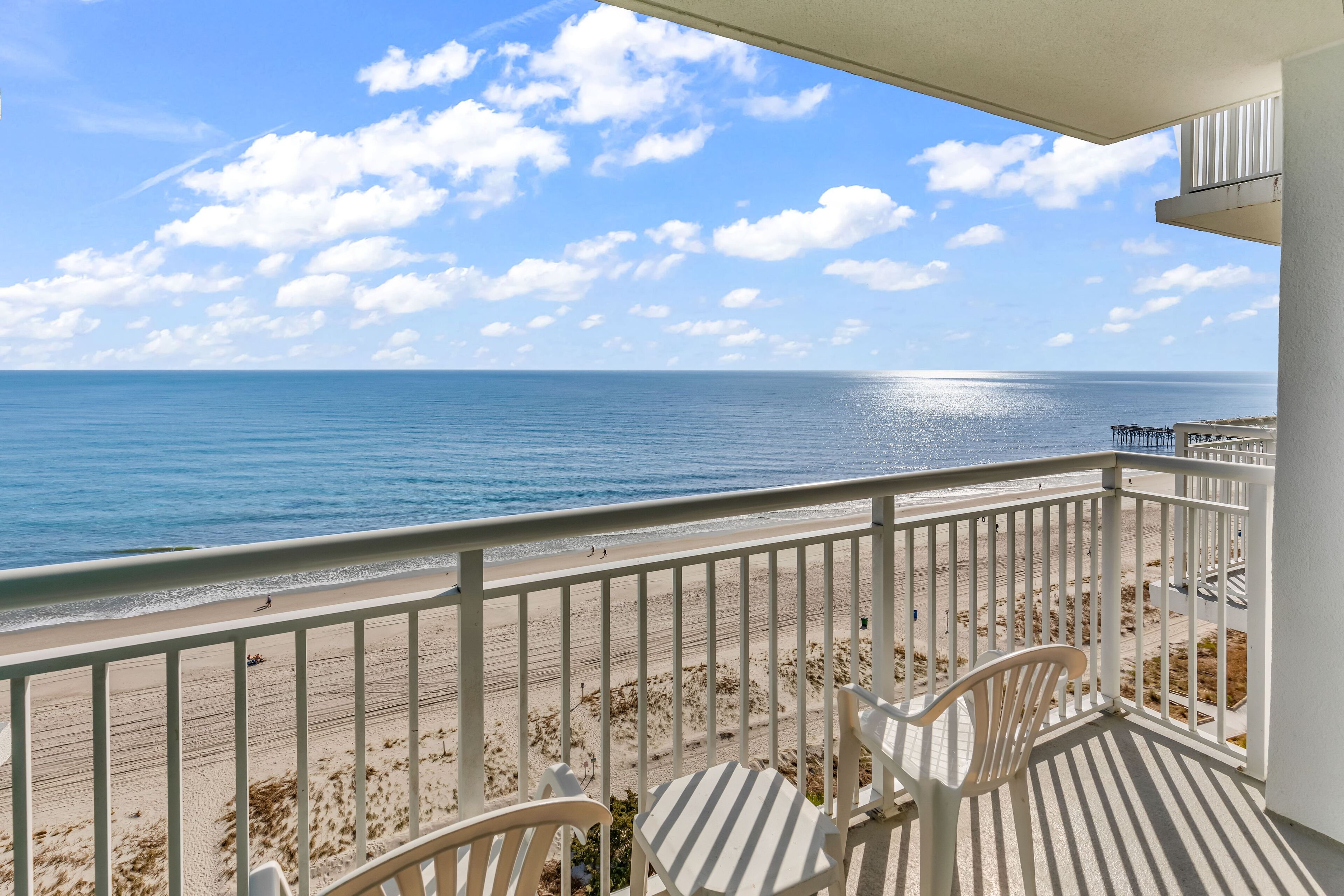 A balcony with a view of the beach and ocean.