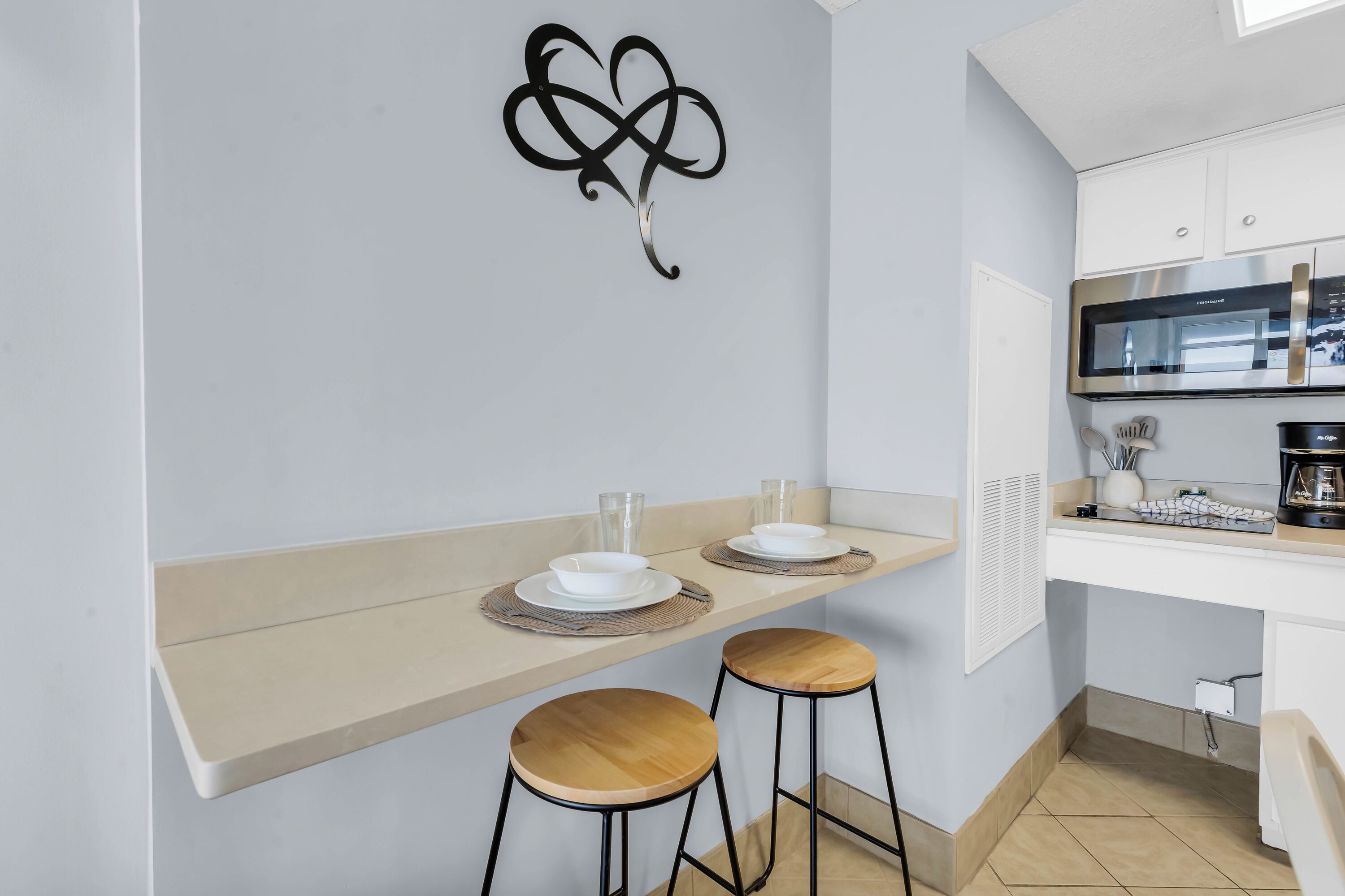 A modern kitchen with a microwave, coffee maker, and a wall-mounted decorative piece.