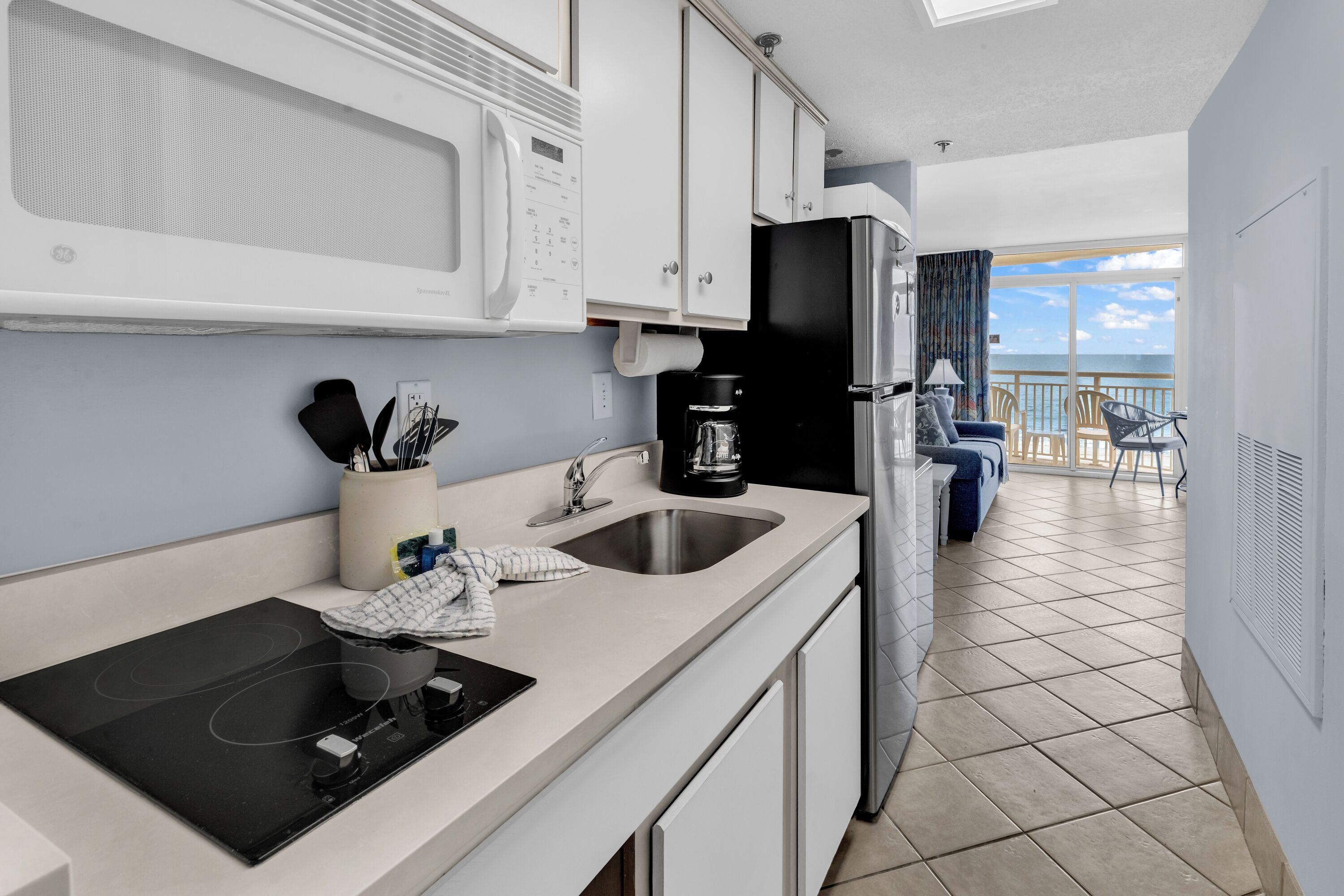 A modern kitchen with a built-in microwave, a coffee maker, and a sink.