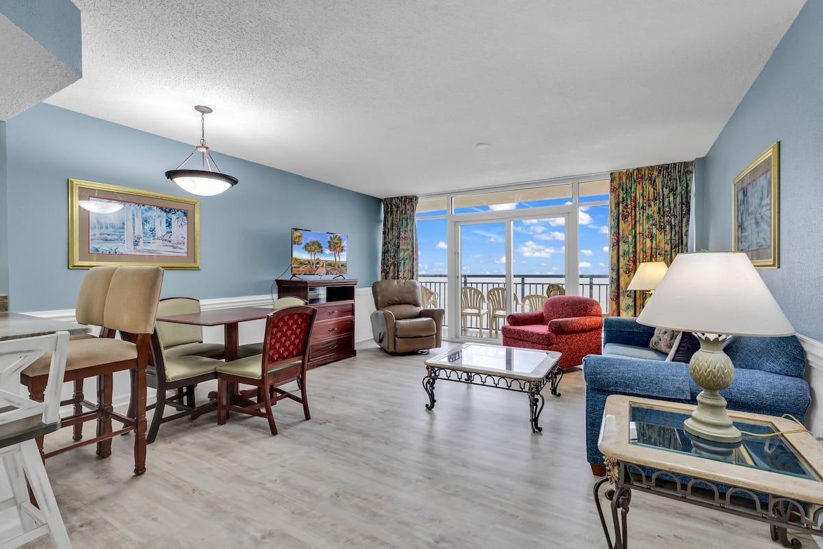 A living room with a dining area, a sofa, a coffee table, and a TV.