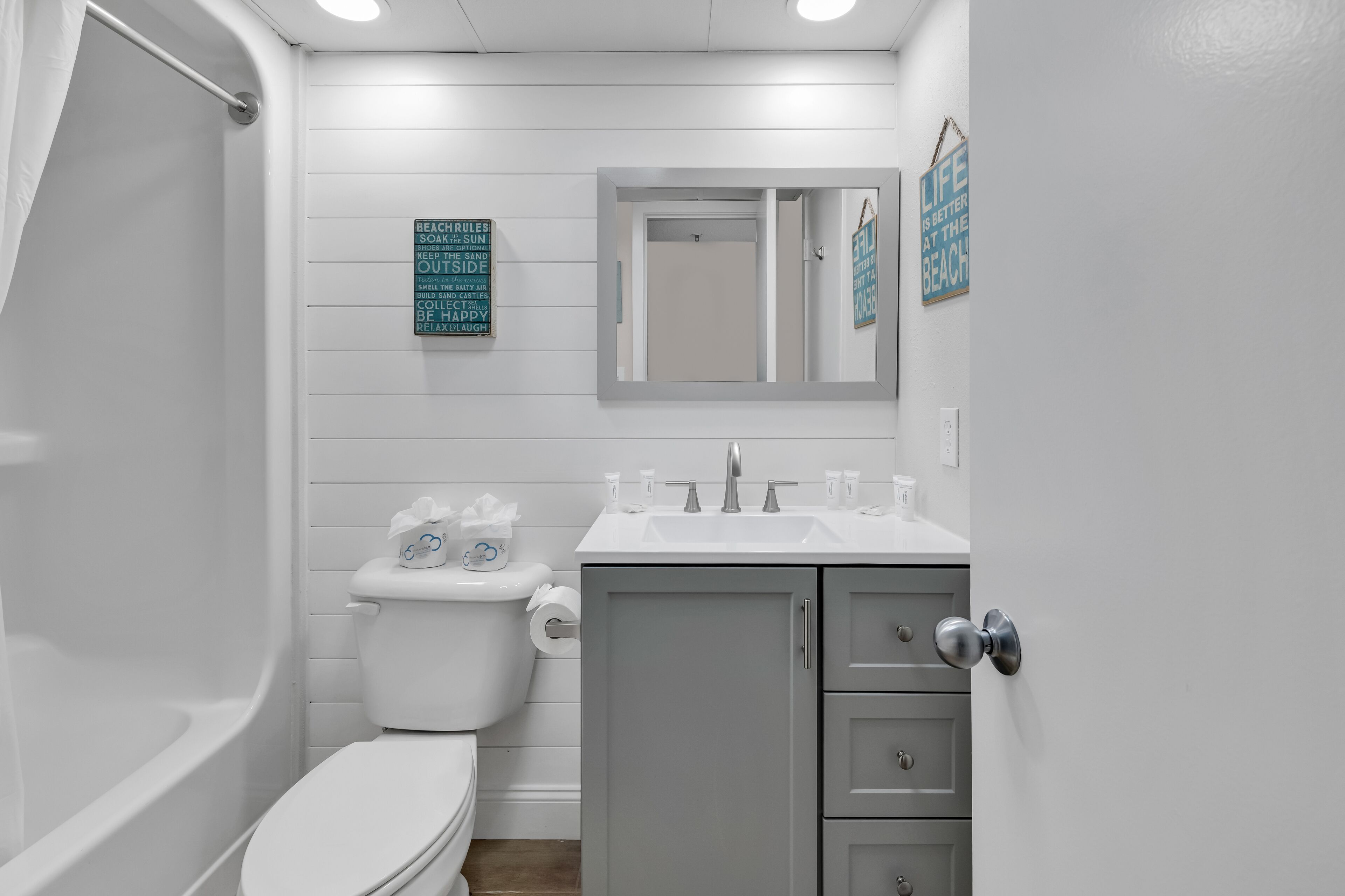 A bathroom with a toilet, sink, and shower. There are signs on the wall with text.