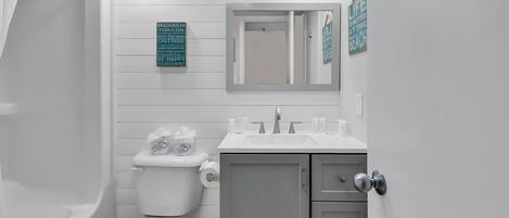 Une salle de bain équipée de toilettes, d’un lavabo et d’une douche. Des panneaux avec du texte sont accrochés au mur.
