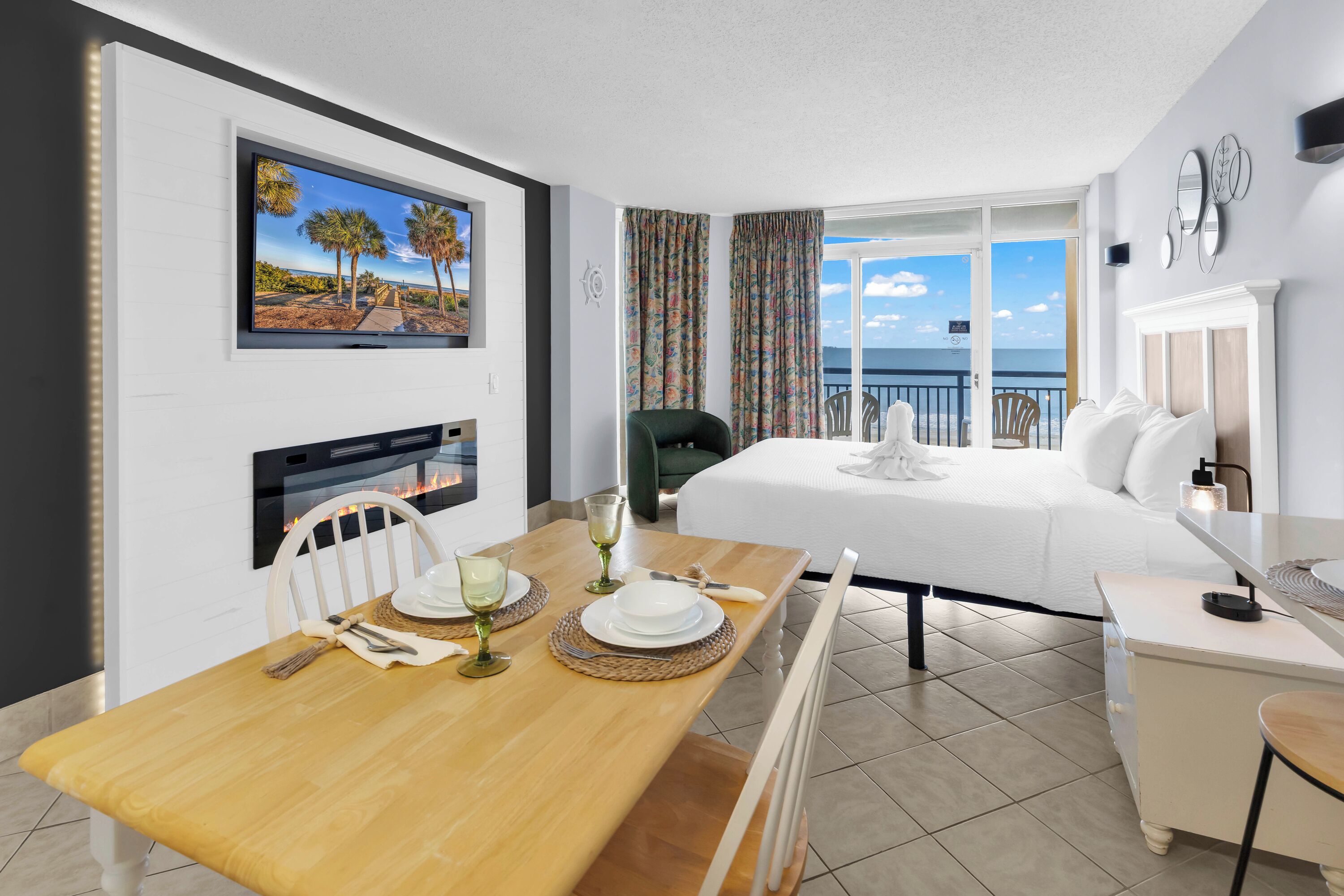 Une chambre d’hôtel comprenant un coin repas, un lit, un balcon avec vue et une télévision.