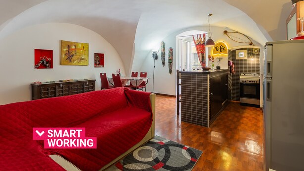 A compact living space with a red sofa, a kitchen area, and a dining set.