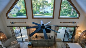 A room with a ceiling fan, large windows, a TV, and a sliding glass door leading to an outdoor area with a grill. - Walk to Dinner! Waterfront, Updated, Prime Location - Back Home Oconee (Eatonton)