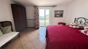 A bedroom with a bed, a chair, a radiator, a window with curtains, and a painting on the wall. - Family-friendly sea-view villa with enclosed garden & BBQ near Sorrento (Sorrento)