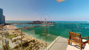 Uma varanda com vista desobstruída para uma praia, uma roda gigante e um calhavem.