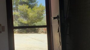 Vista através de uma porta para um estacionamento com árvores ao fundo.