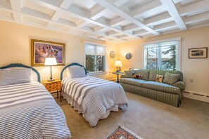 A bedroom with two beds, a sofa, and a window with a view.