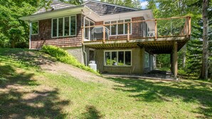 A two-story house with a wooden deck and a covered outdoor area. - Coastal Hideaway. Water views with expansive deck, pool table, office area. (Harpswell)