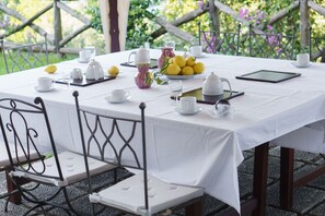 Ein Tisch ist für ein Teeservice gedeckt, mit weißer Tischdecke, Teekannen, Tassen und einer Zitronentellert.