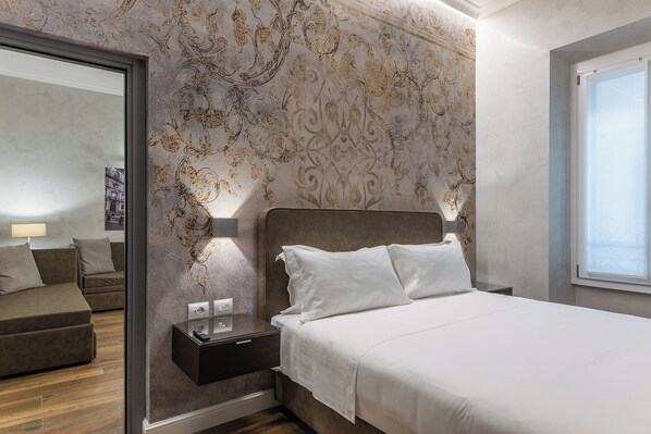 A bedroom with a bed, a nightstand, a dresser, a mirror, and a window.