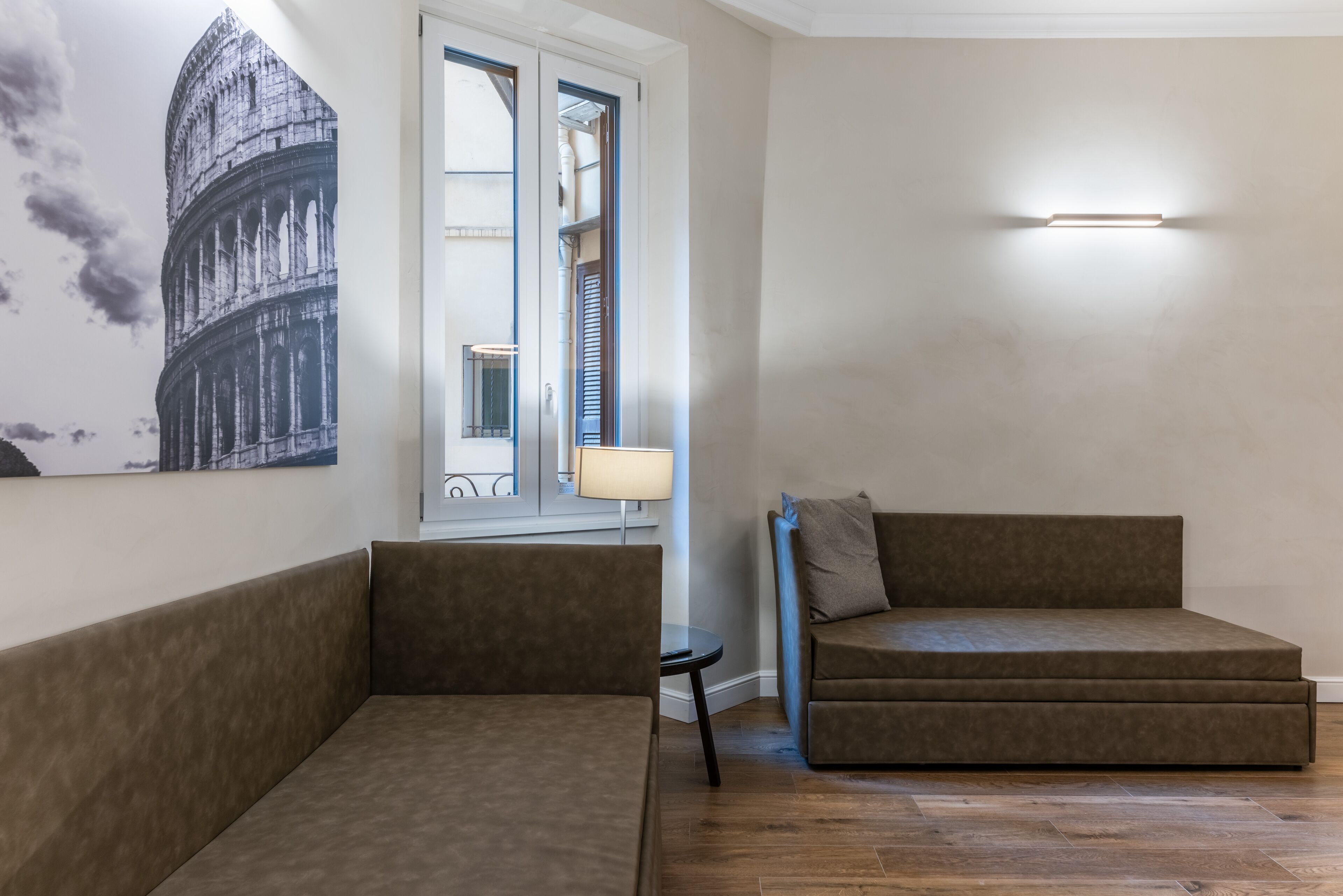 Una sala de estar moderna con dos sofás, una lámpara y un aplique de pared.