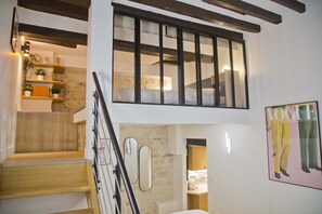 Una escalera de madera con peldaños que conducen a un dormitorio en el segundo piso, con un ventanal grande.