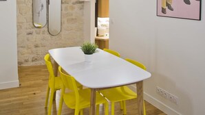 Uma sala de jantar com uma mesa branca e cadeiras amarelas, uma parede de pedra e um quarto no mezanino.