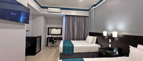A hotel room with two beds, a desk, a TV, and a mirror.