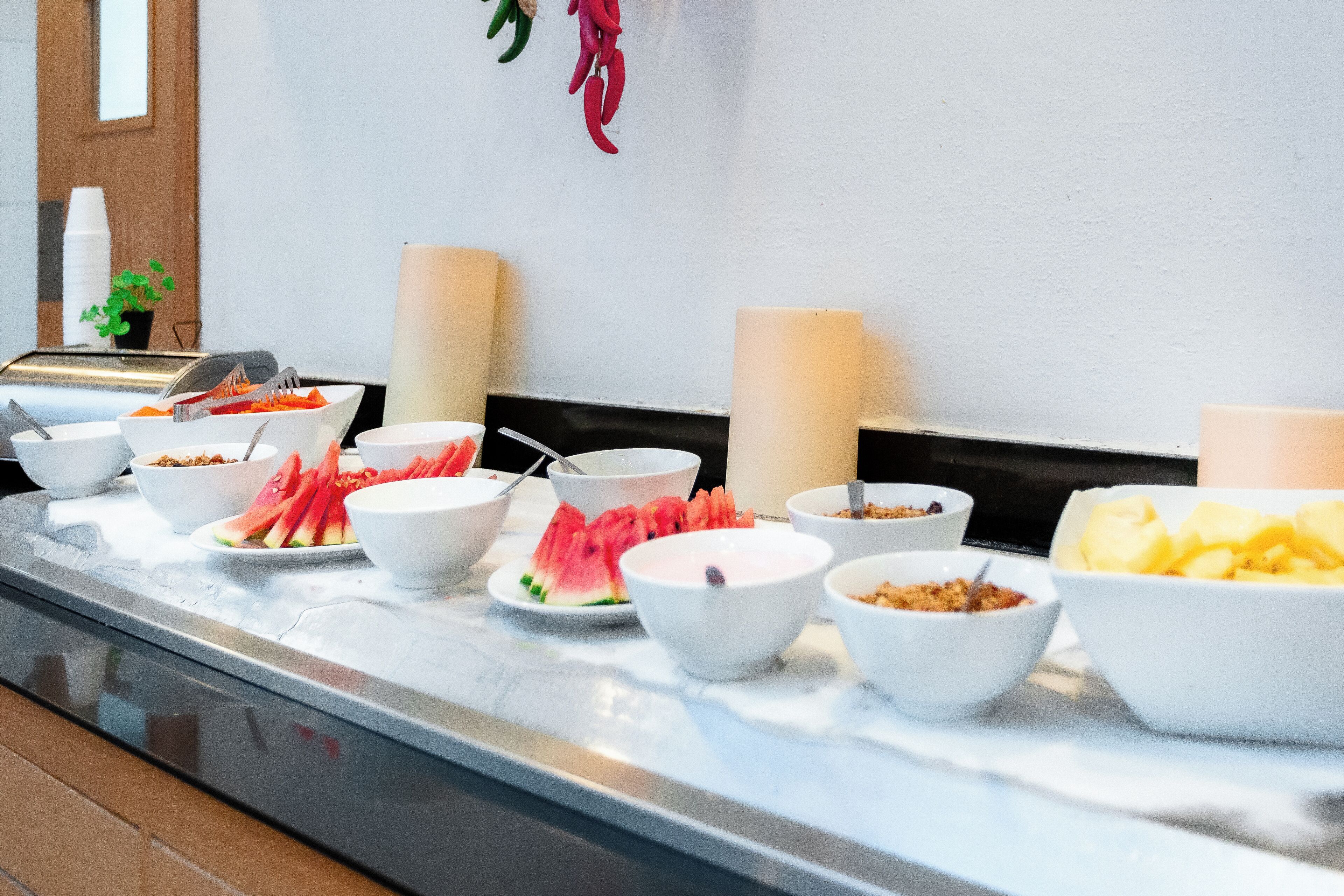 A buffet setup with various food items and bowls on a marble countertop.