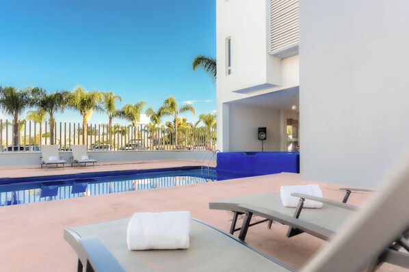A modern pool area with lounge chairs and a clear view of palm trees.