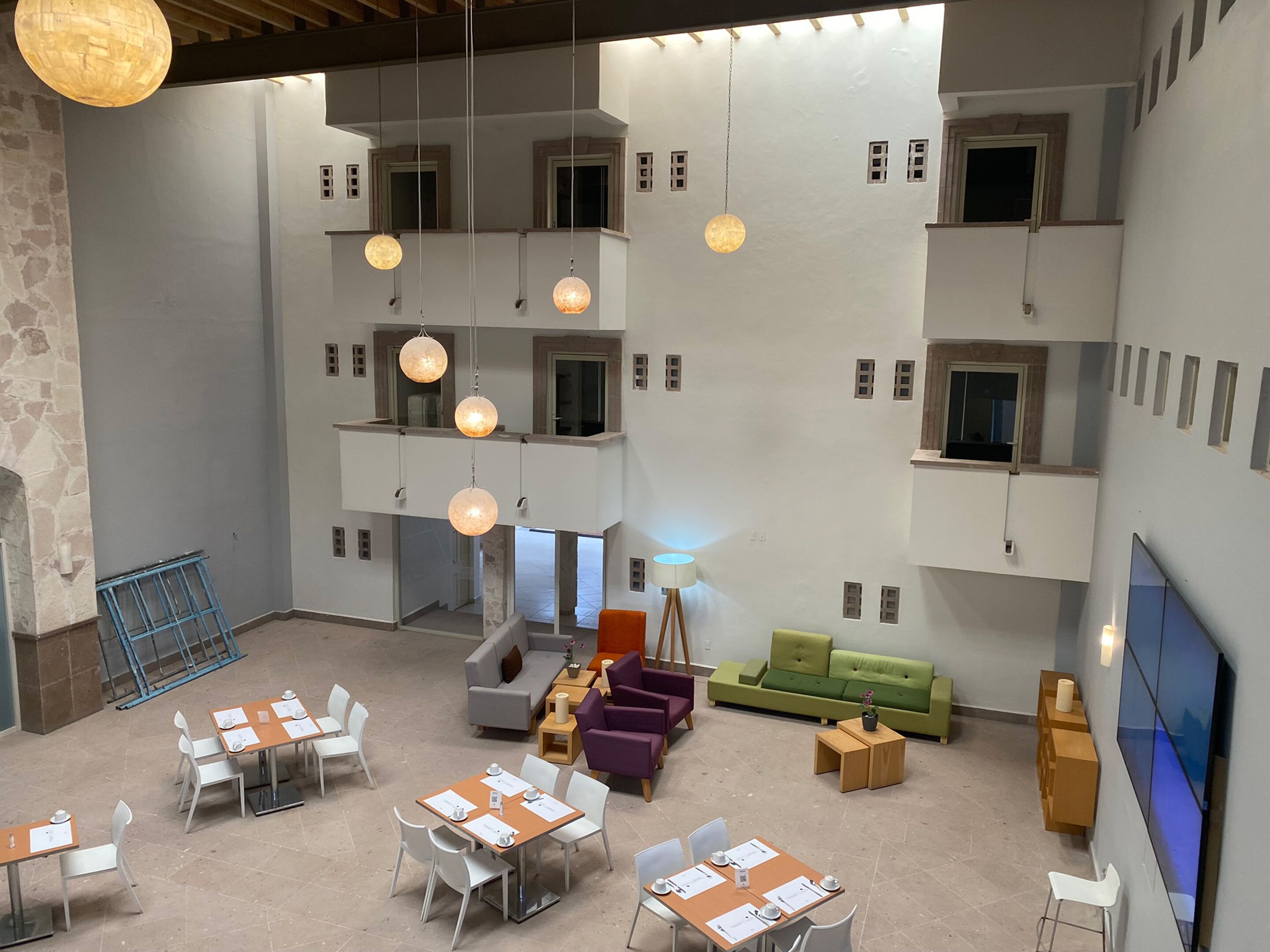 Un interno spazioso e moderno con diverse aree pranzo, posti a sedere e lampade sferiche sospese.