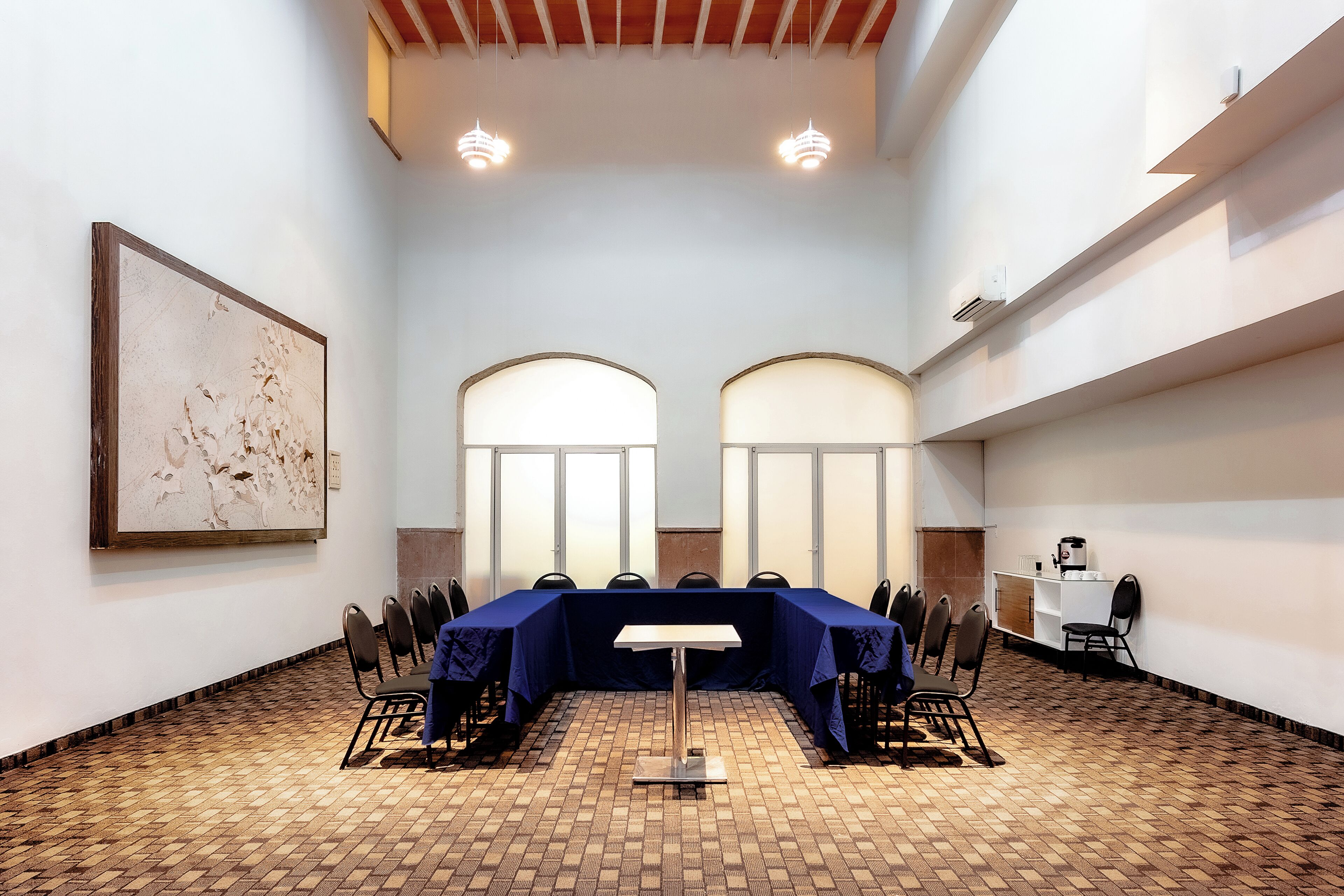 Un salón de conferencias con una larga mesa, sillas y un cuadro abstracto grande en la pared.