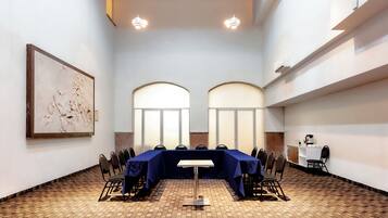 Un salón de conferencias con una larga mesa, sillas y un cuadro abstracto grande en la pared.