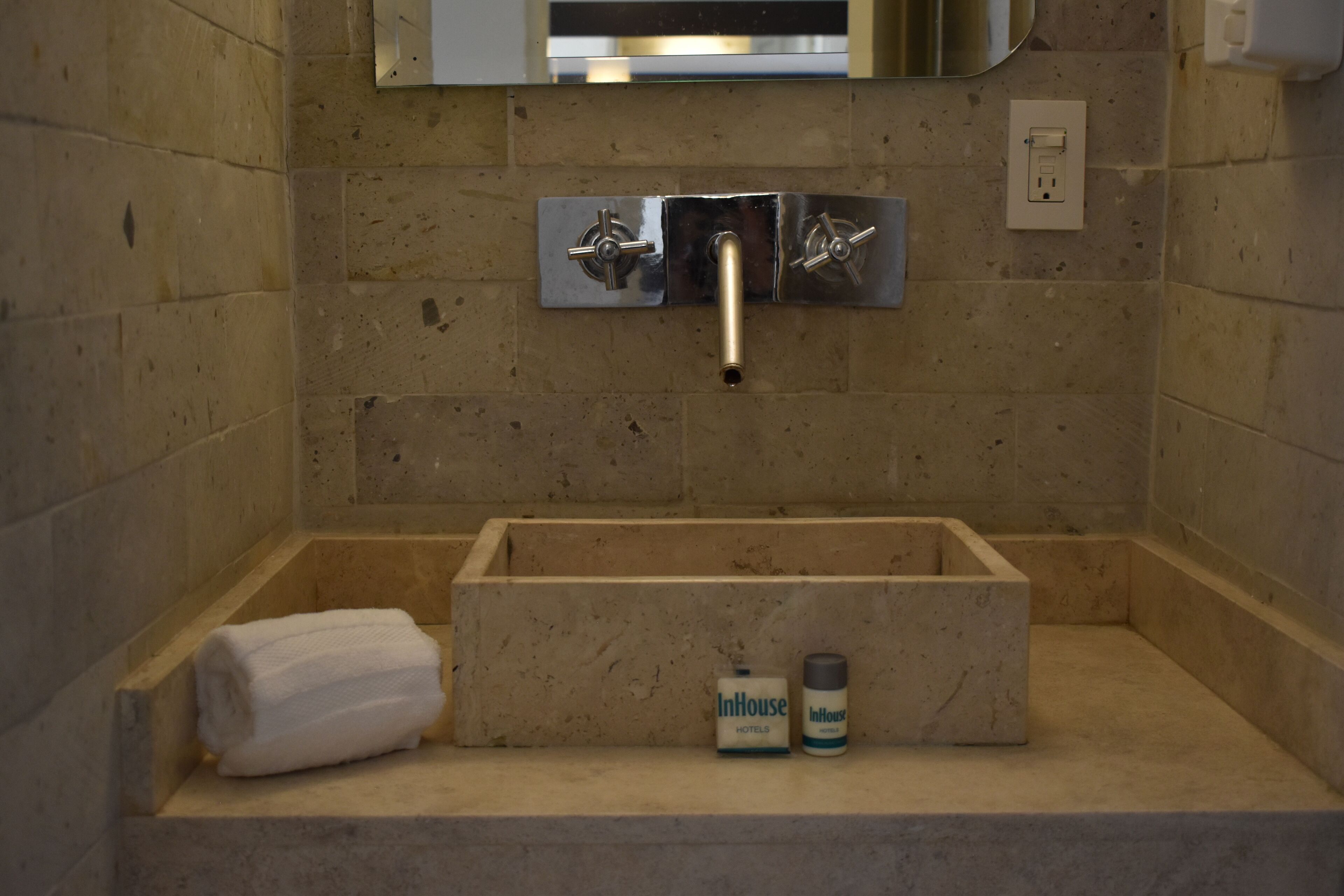 A bathroom with a marble sink, a towel, and toiletries.