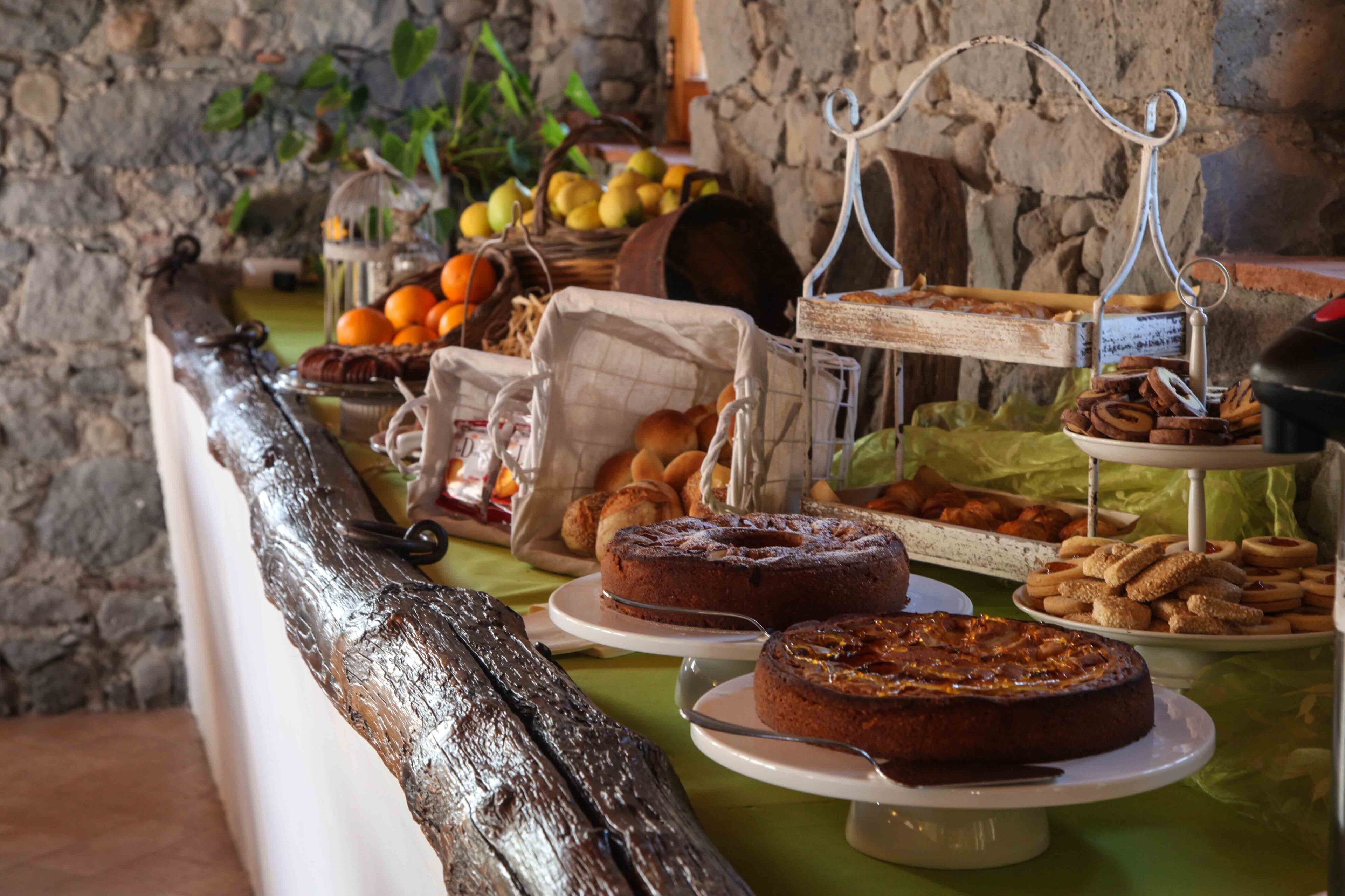Taula de buffet amb diferents productes de forneria, com ara pastissos i forns, disposats sobre plats i suport blanc.