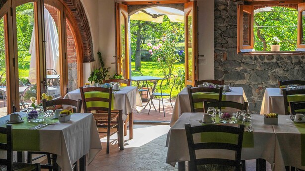 A restaurant with outdoor seating, stone walls, and a view of a garden. - Agriturismo Galea (Riposto)